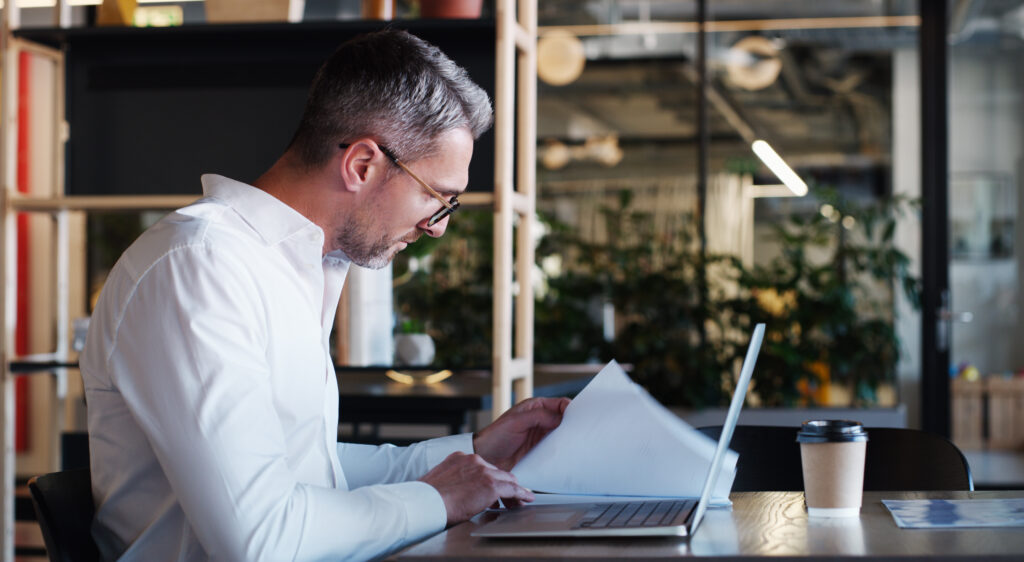 businessman accountant and documents with laptop for AI Tools in Your Business Contracts: What Every Atlanta Company Needs to Address Before Problems Arise