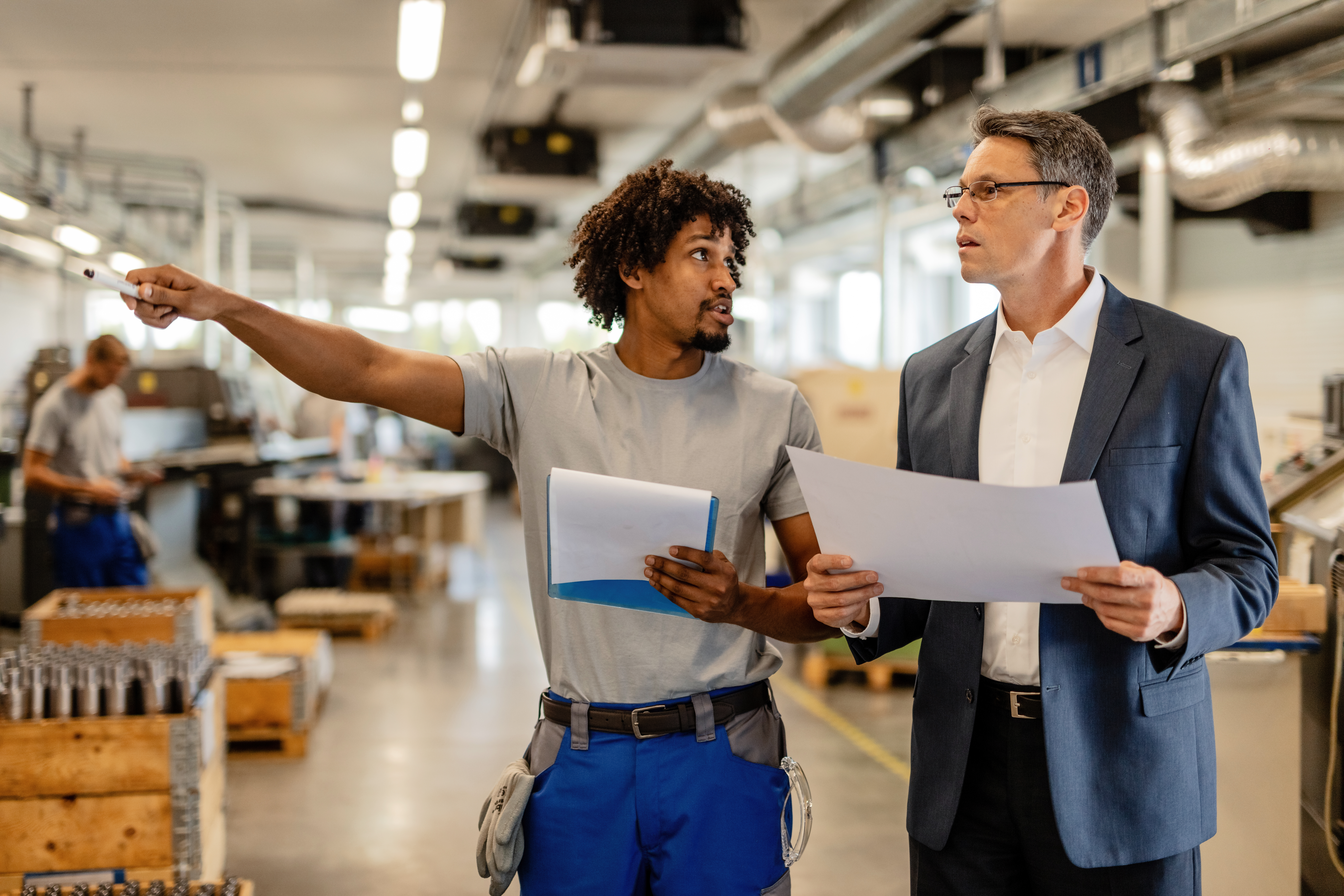 two men reviewing blueprints at manufacturing work for What to Expect From M&A Due Diligence: A Small Business Guide for Buyers and Sellers in Atlanta