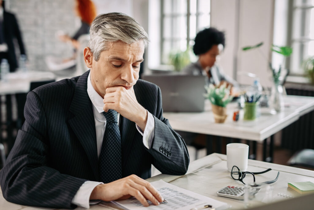 serious businessman examining business reports in for Personal Guarantees in Georgia Business Contracts: When You Sign One, You're Putting Your Personal Assets on the Line